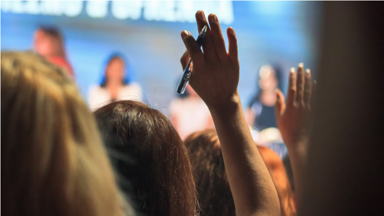 People in a meeting raising hands