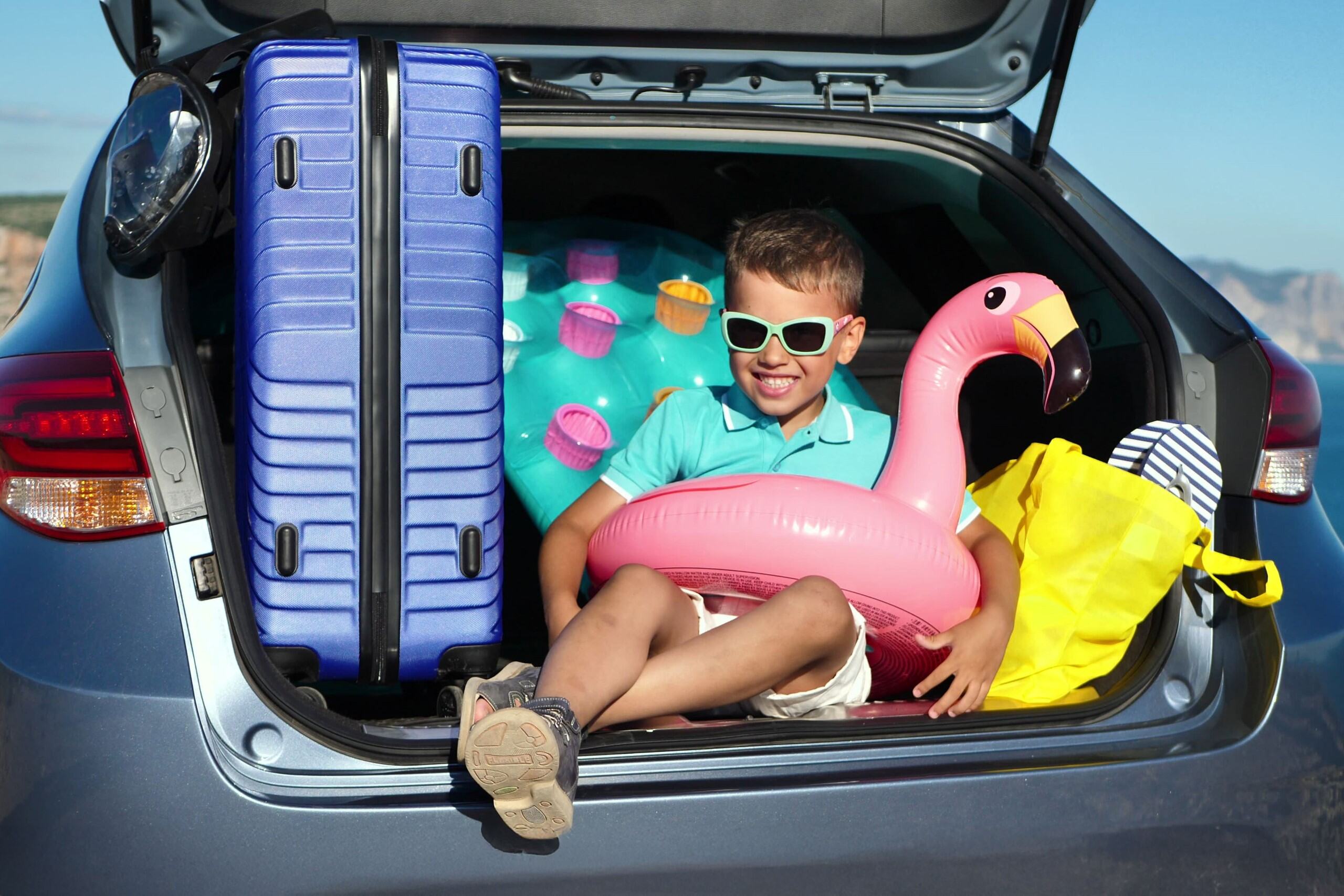 Kid in sunglasses sitting in car boot