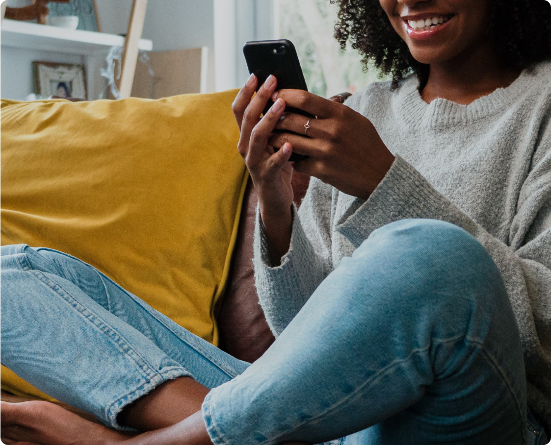 Woman, cross-legged on sofa, watching video on phone
